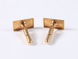 two pairs of gold cufflinks on a white surface