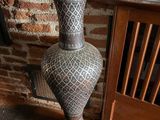 a vase sitting on the floor next to a brick wall