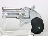 a silver revolver on a clear stand on a white surface