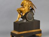 an antique bronze statue of a man sitting on top of a clock