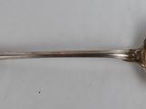 une cuillère ancienne en argent dont le manche repose sur une surface blanche