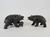 two black bears standing next to each other on a white surface