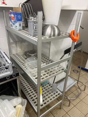 une cuisine équipée d'une cuisinière, d'un évier et d'une étagère en métal