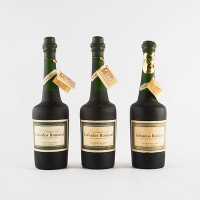 trois bouteilles de vin posées les unes à côté des autres sur une surface blanche