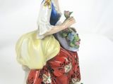 a figurine of a woman sitting on a flower pot