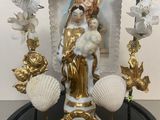 a statue of the virgin of guadalupe surrounded by flowers and seashells