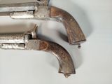 pair of old silver revolvers sitting on a white surface