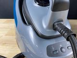 an image of a blue and black steam iron on a wooden table