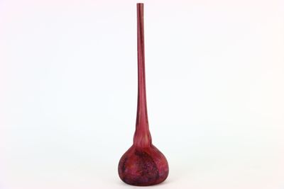 un vase rouge posé sur une surface blanche