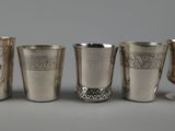 four silver cups and a silver goblet on a table