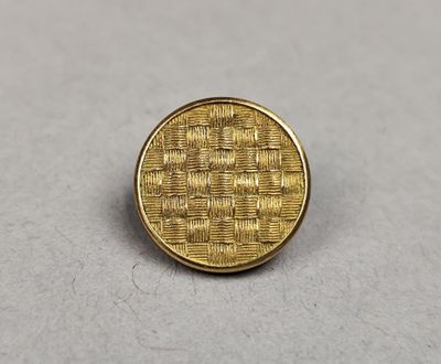 a close up of a gold colored pin with a woven design