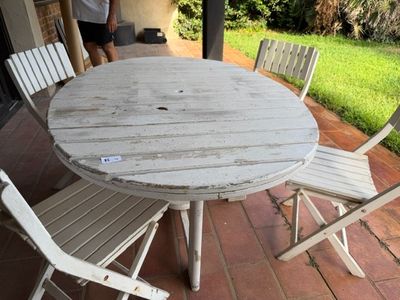 une table et des chaises sur une terrasse, avec un homme à l'arrière-plan