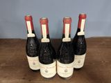 three bottles of red wine are lined up on a wooden table