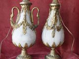 two white and gold vases on a red cloth with a red background