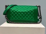 a green quilted handbag sitting on top of a white box