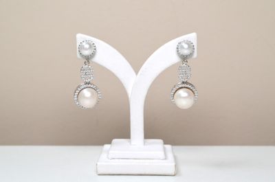 pair of white pearl and crystal earrings on a white stand