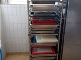 Plusieurs plateaux de nourriture sont empilés sur un chariot dans une cuisine
