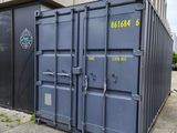 un conteneur d'expédition bleu posé devant un immeuble