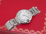 une montre argentée posée sur une boîte rouge, elle-même posée sur une surface rouge