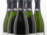 six bouteilles de vin sont alignées sur une surface blanche