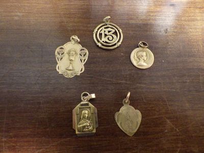 plusieurs breloques en argent et en or posées sur une table en bois, à côté d'une photo de femme