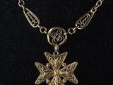 a gold necklace with a cross pendant on a black mannequin