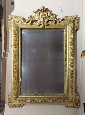 a gold framed mirror on the wall in a room