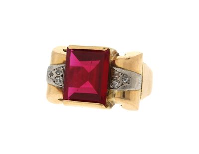 un gros plan d'une bague sertie d'une pierre rouge et de diamants