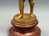 une statue antique en bronze représentant un homme tenant une batte de baseball