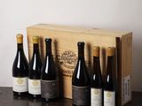 six bouteilles de vin sont posées dans une caisse en bois sur une table
