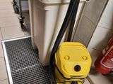 un aspirateur jaune posé par terre à côté d'une poubelle