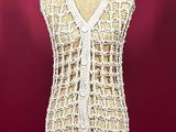 white crocheted vest on a mannequin stand against a red background