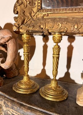 trois bougies dorées posées sur une cheminée, avec un miroir en arrière-plan