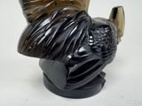 a black vase with a bird on it on a table