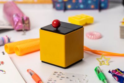 a small yellow box with a red ball on top of it