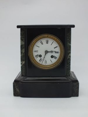 une petite horloge noire avec des chiffres romains