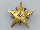 un gros plan sur une broche en forme d'étoile en or sertie de diamants