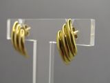 boucles d'oreilles plaquées or posées sur un support en acrylique transparent, sur fond gris