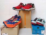 three pairs of running shoes sitting on top of boxes on a white surface