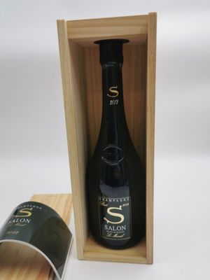 une bouteille de vin dans un coffret en bois, à côté d'une tasse