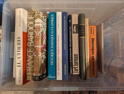 de nombreux livres dans une boîte en plastique posée par terre