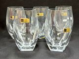 three clear wine glasses with yellow labels on them on a black surface