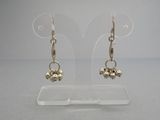 une paire de boucles d'oreilles plaquées argent sur un support en acrylique transparent