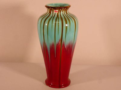 un vase rouge et bleu posé sur une table blanche