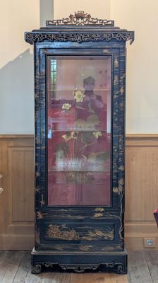 une armoire haute ornée d'un tableau, dans une pièce