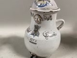 un vase blanc muni d'un couvercle, posé à côté d'un vase surmonté d'une tasse