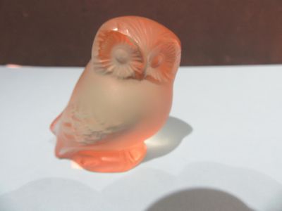 une figurine de chouette orange posée sur une table blanche