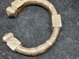 gros plan d'un bracelet en or sur une surface noire