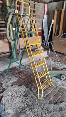 a yellow ladder that is next to a pile of wood