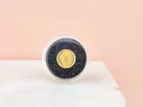 a gold and black coin ring sitting on top of a white block